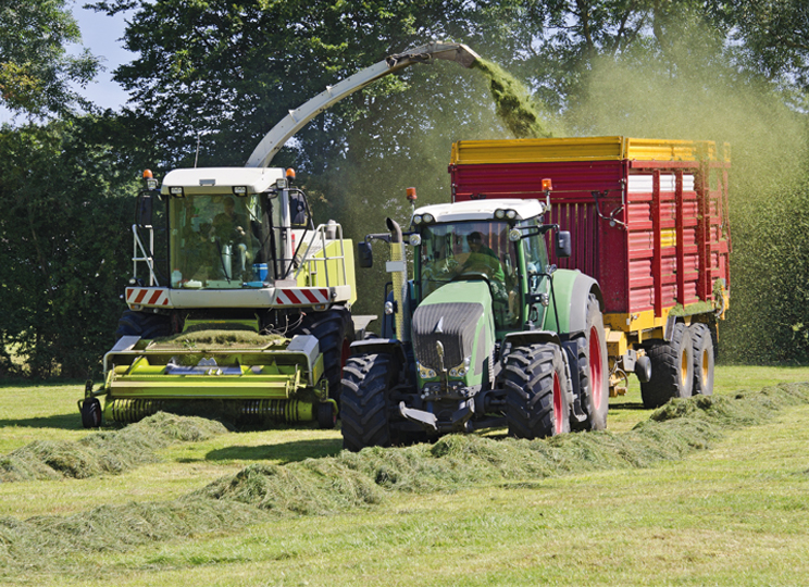 harvester and tractor collecting hay